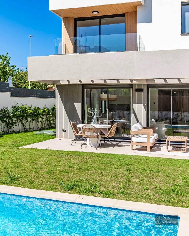 View of a luxurious villa with a pool and lush garden. Modern architecture featuring large windows and high-quality materials.