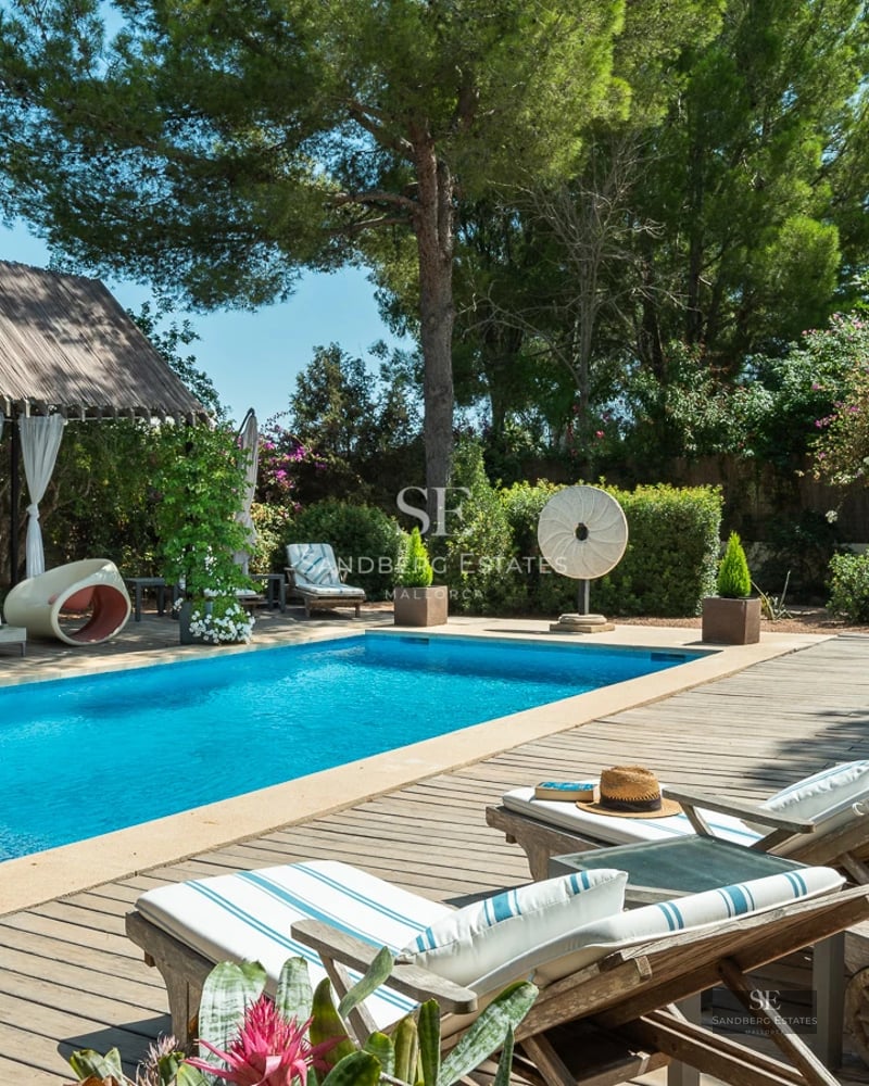 Exterior view of a modern villa with reflecting pool, large windows, glass balcony, and lush garden. Minimalist architecture.