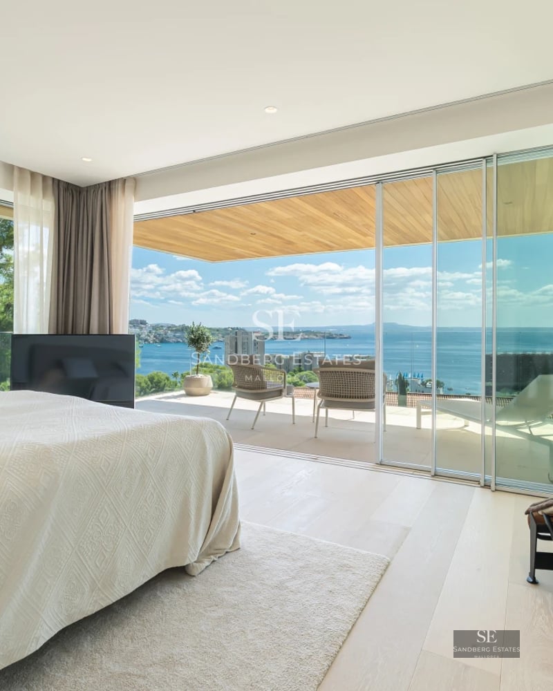 Spacious living room with a modern fireplace and large windows overlooking the lush garden. Elegant furniture and design details.