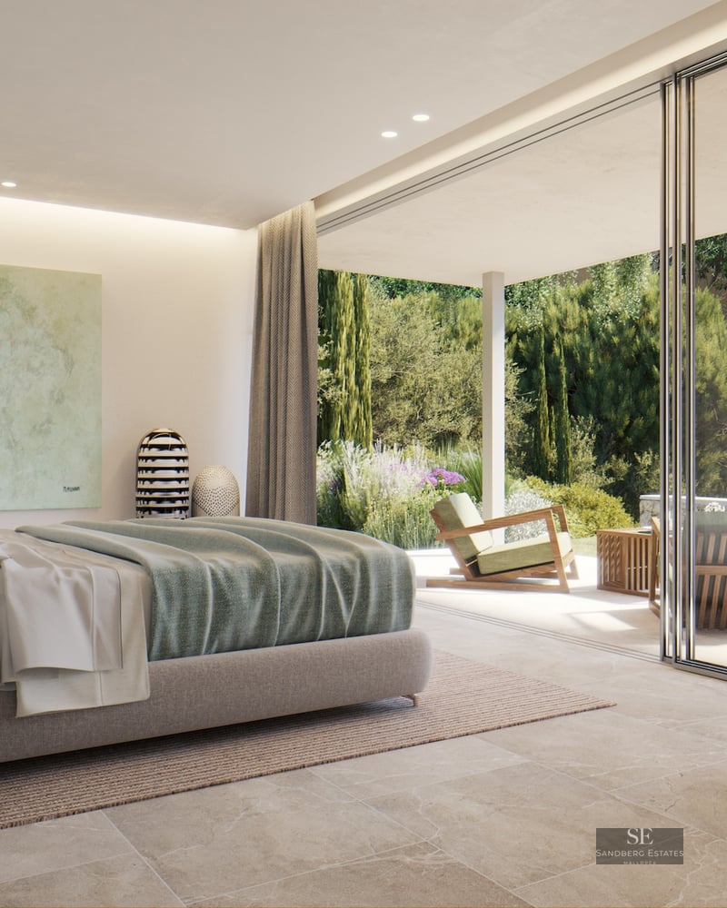 Modern bedroom with large sliding glass doors opening to a sunlit terrace and lush Mediterranean garden.