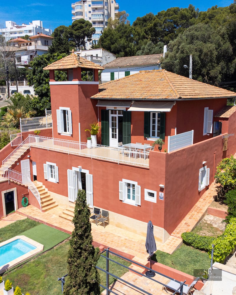Aerial view of a terracotta-red villa with a private swimming pool, lush garden, and multiple sun terraces.