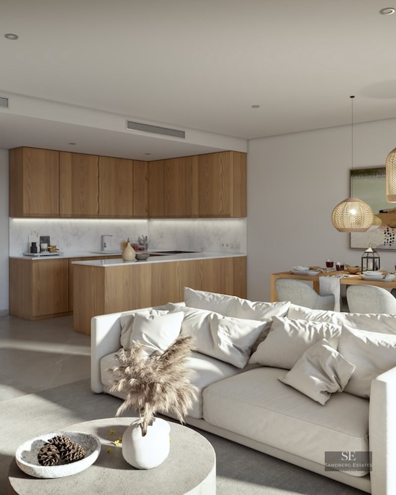 Modern living room with a white sofa, wooden dining table, and contemporary kitchen with wood and marble finishes.