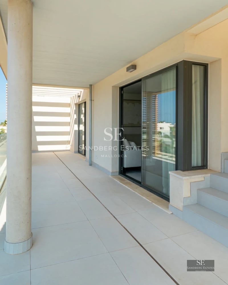 Spacious balcony with sea view. Modern outdoor furniture, glass railing, and tiled floor. Contemporary design.