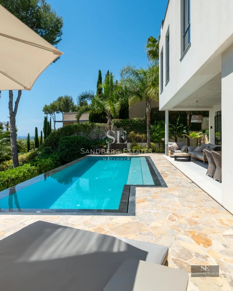 Exterior of a modern villa with an infinity pool. Minimalist architecture, manicured garden and unobstructed views. Stone and wood details.