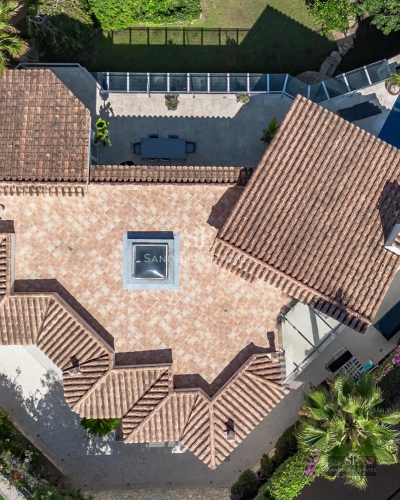 Exterior view of a modern villa featuring an infinity pool, lush gardens, and contemporary architectural design. Soft ambient lighting.