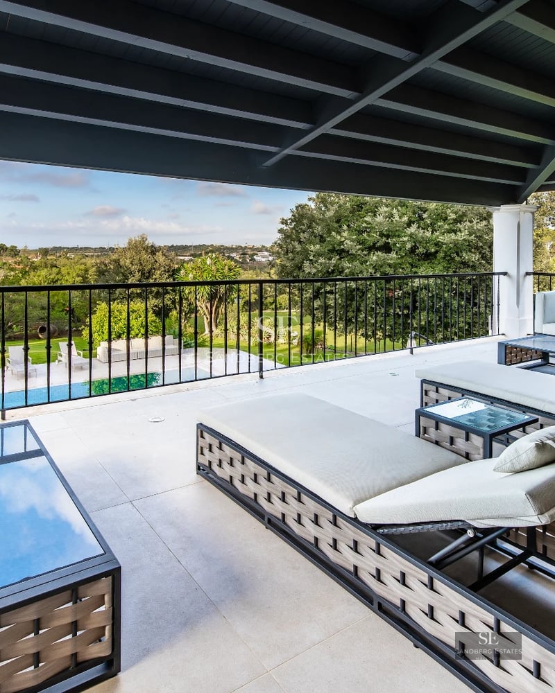 View of infinity pool and garden of a modern villa with stylish outdoor furniture and lush landscaping design.