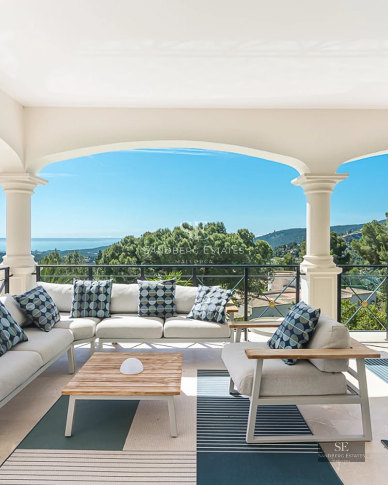 Spacious sea view balcony with modern furniture, glass railing, gray tile flooring, and retractable awning.