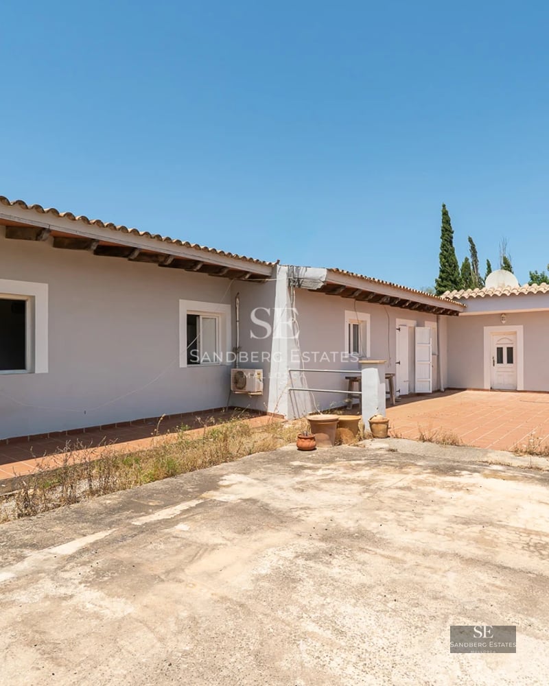 View of a luxurious pool surrounded by a lush garden, with a modern house featuring large windows and minimalist architecture.