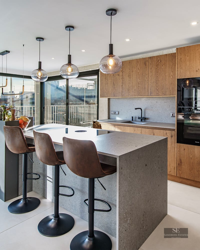 Modern kitchen featuring a stone island with three leather stools, wood cabinetry, and large windows with urban views.