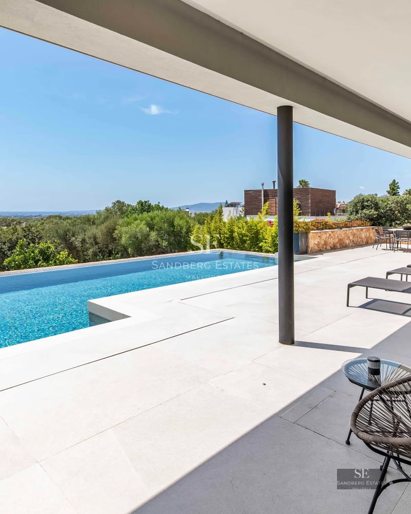 Exterior of modern villa with infinity pool, lush garden, and minimalist architecture. Warm sunset lighting.