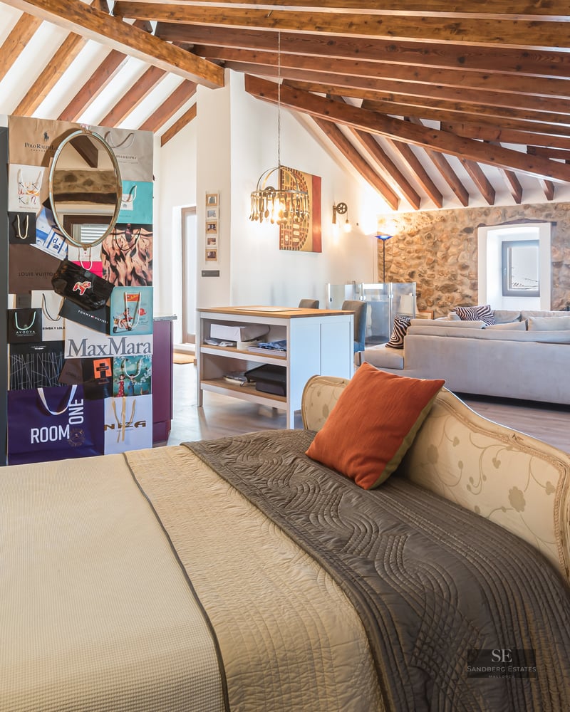 Luxury bedroom featuring exposed wooden beams, natural stone walls, and an integrated living area.
