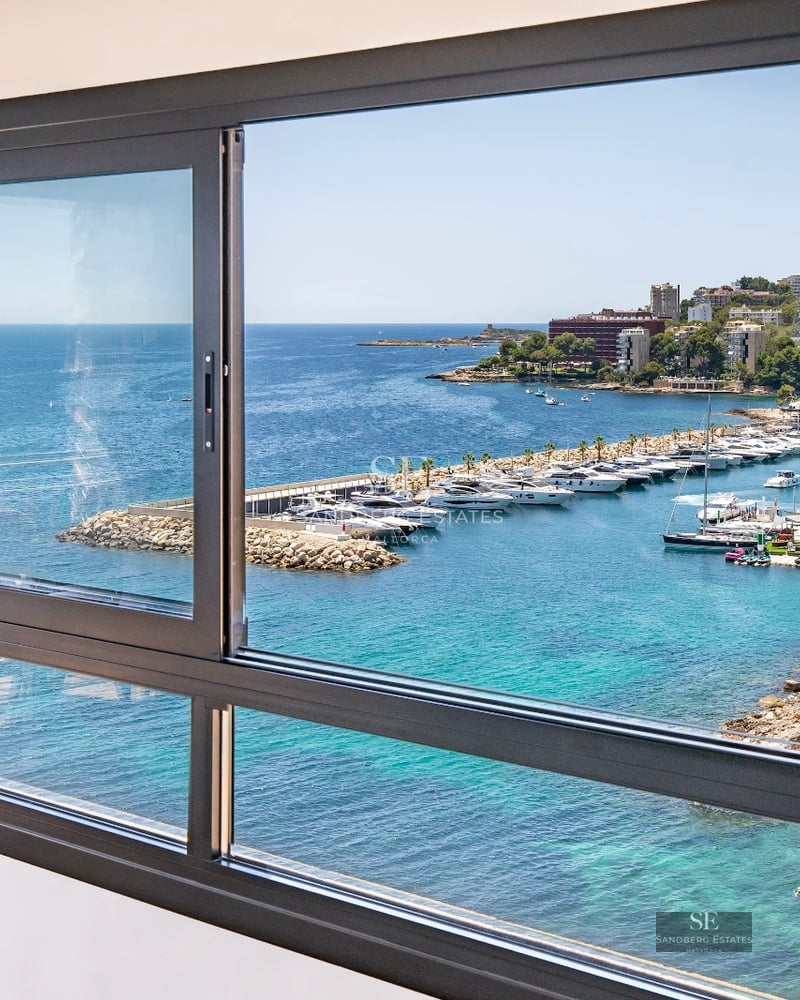 Spacious balcony with sea view. Modern design, glass railing, outdoor furniture. Natural and warm lighting.