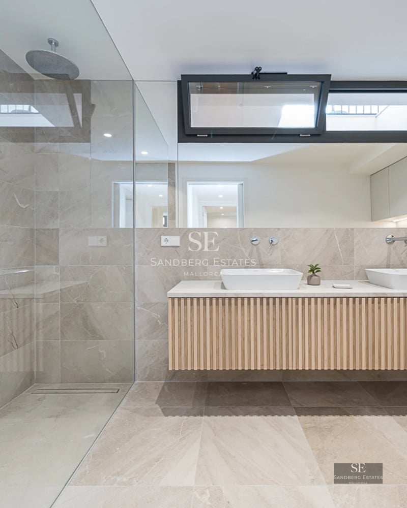 View of pool with sun loungers, outdoor armchairs, and modern facade with large windows. Blue sky and greenery.