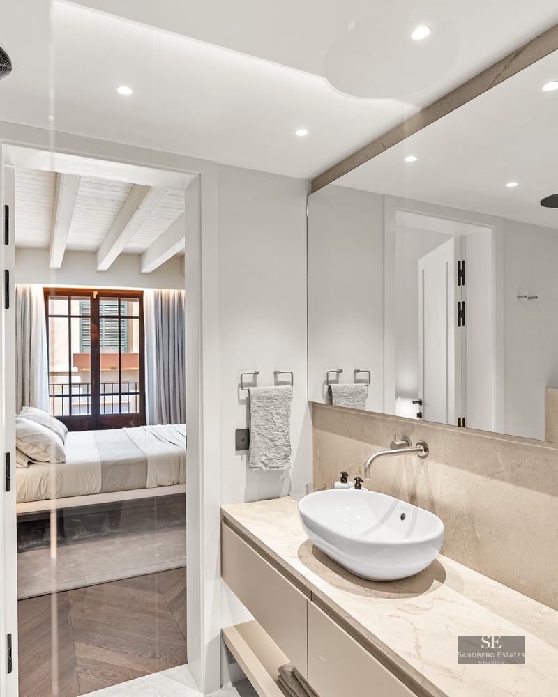 Luxury bathroom featuring a stone countertop, oval vessel sink, and a view into a bright bedroom.