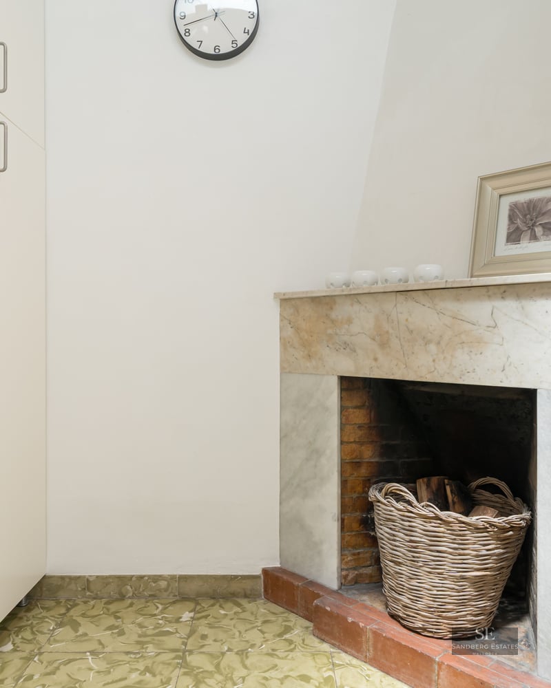 Interior corner featuring a marble fireplace, a wicker wood basket, and a tall white storage cabinet.