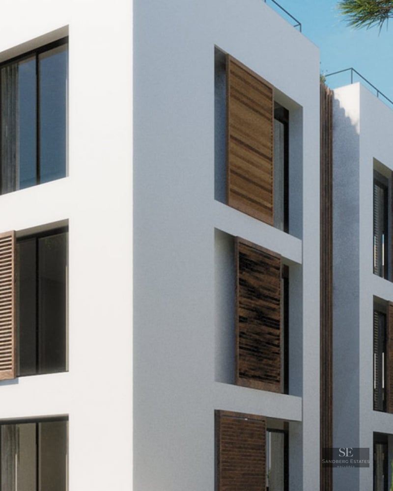 Modern white multi-story building featuring sliding wooden shutters and large windows under a clear blue sky.