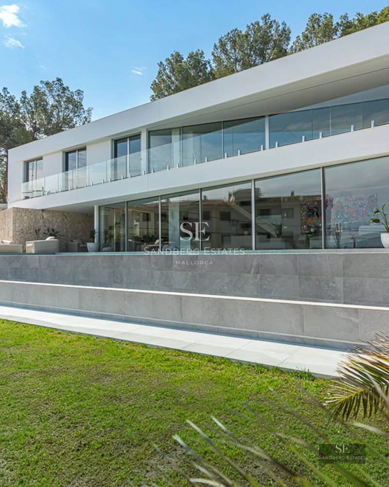 Spacious terrace with a pool surrounded by greenery. Modern design with wooden floors, glass windows, and panoramic views. Elegant outdoor furniture.