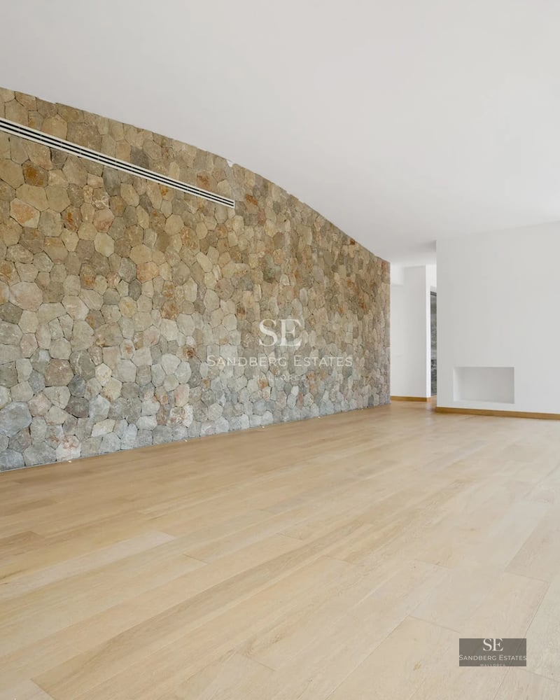 Spacious living room with fireplace, large windows, and access to a terrace with a pool. Modern and elegant design with abundant natural light.