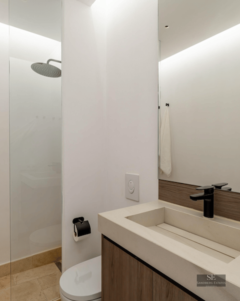 Modern bathroom featuring a stone sink, black fixtures, and a walk-in glass shower with rain showerhead.