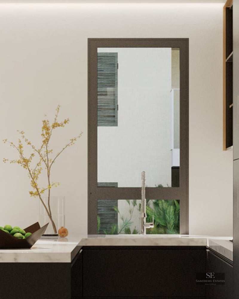 Minimalist kitchen with black cabinets, white marble counters, and a view to an outdoor courtyard.