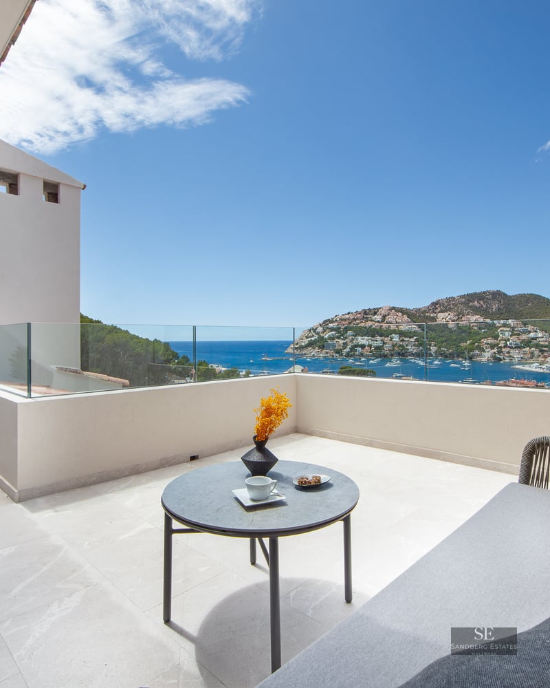 Luxury terrace with glass railings, outdoor sofa, and a breathtaking view of a Mediterranean harbor.