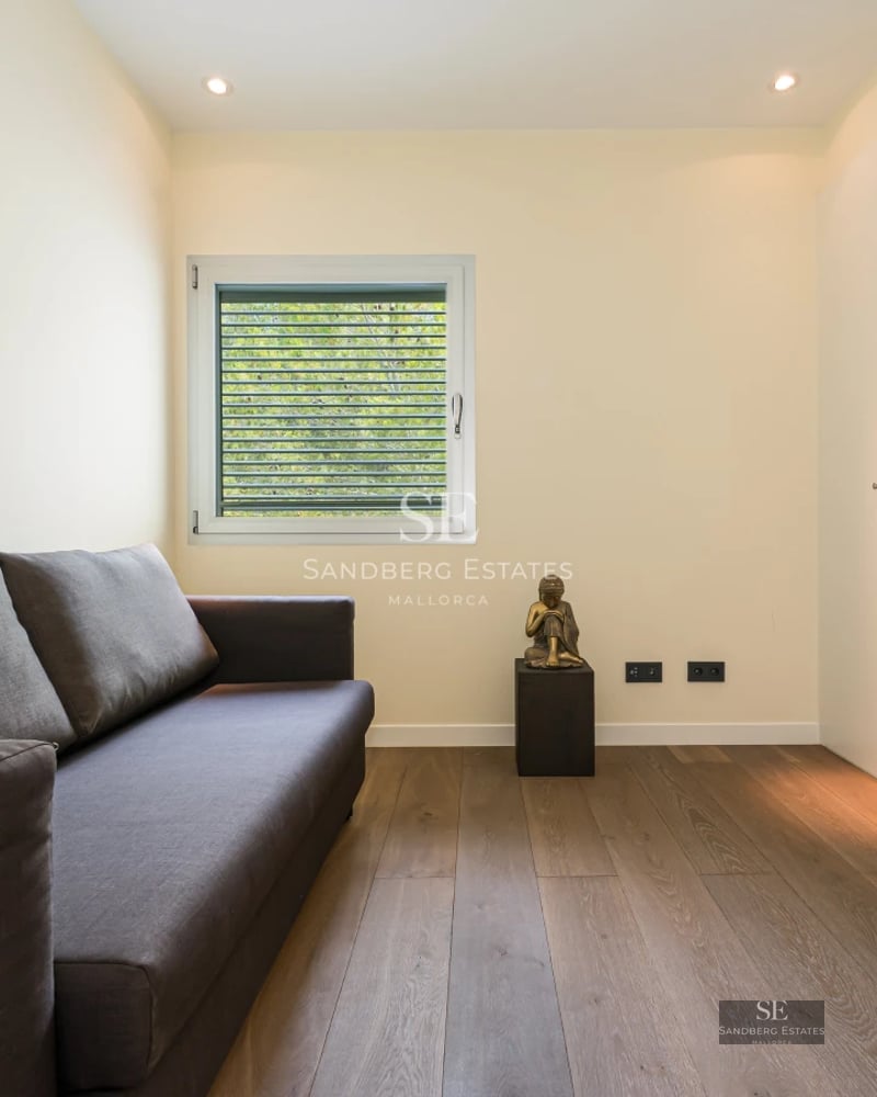 Spacious, bright living room with large windows, light wood floors, and modern furniture. Garden view. Minimalist and elegant design.