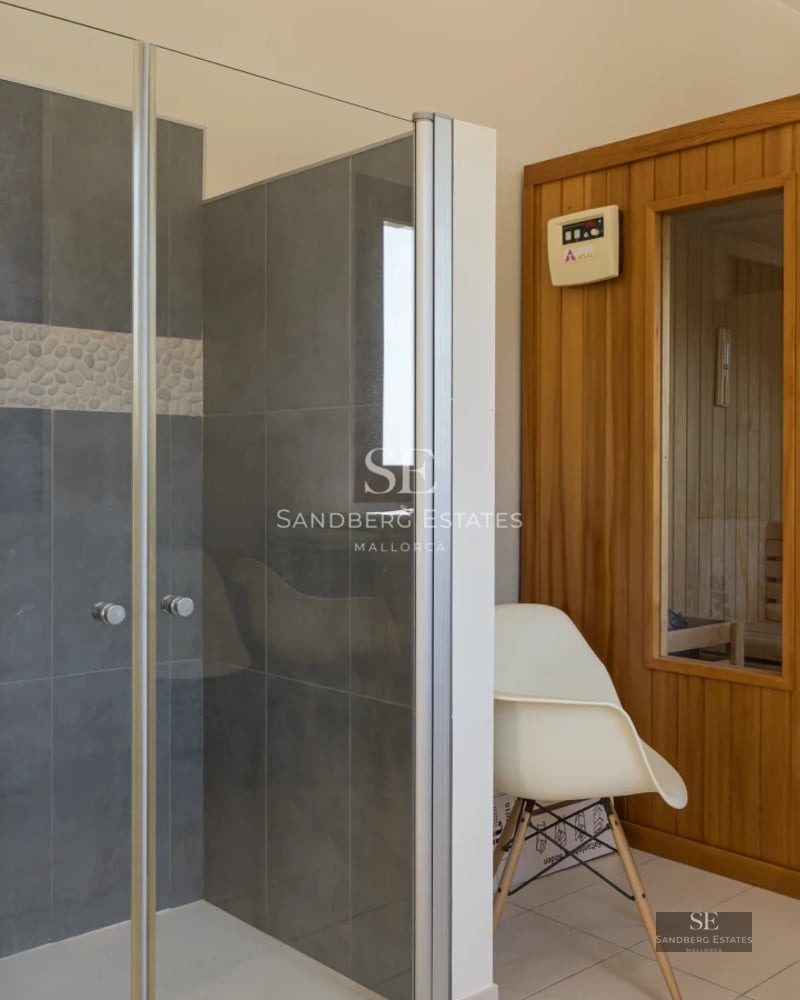 Infinity pool view with glass edge, sun loungers, lush greenery, and modern design. Clear blue sky.