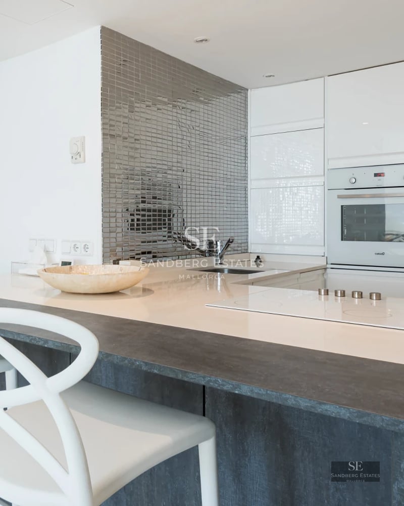 Spacious balcony with panoramic sea view. Glass railing, wooden floor, and modern outdoor furniture. Natural light.