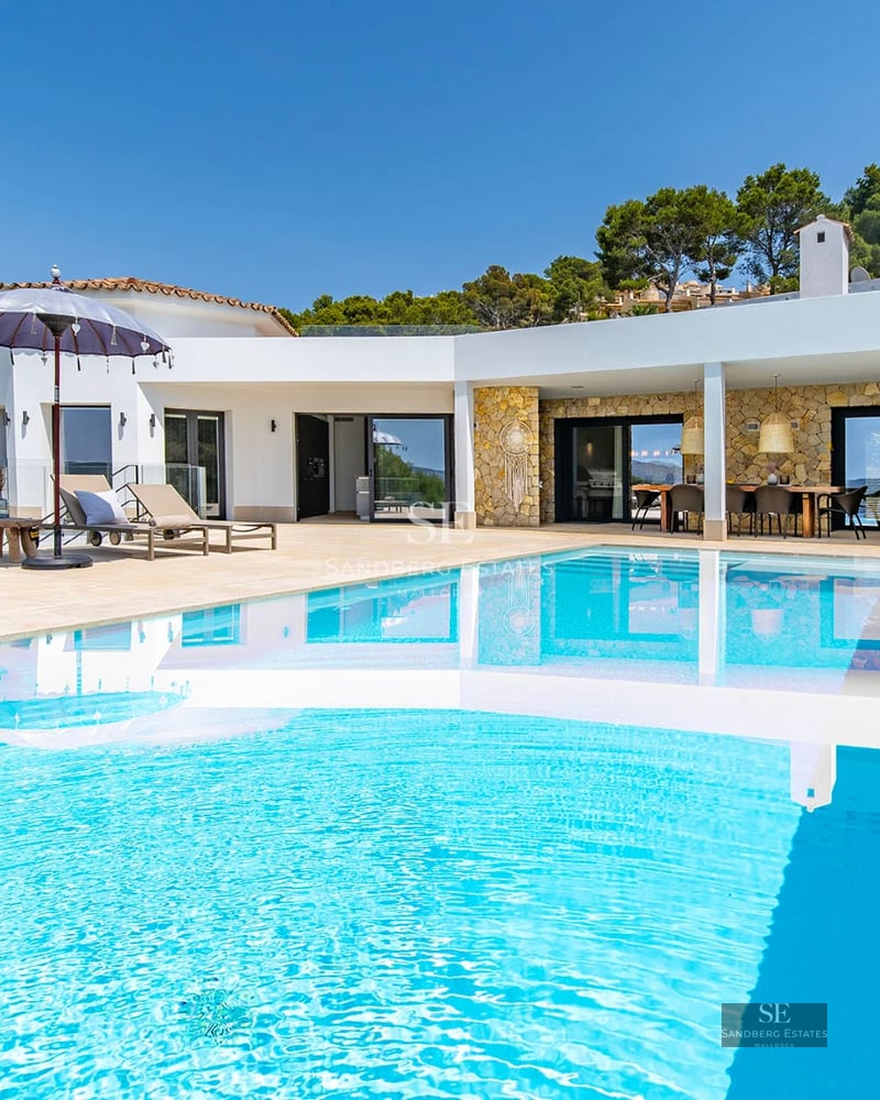 Bright living room with large windows, light wood floors and modern furniture. Panoramic sea views.