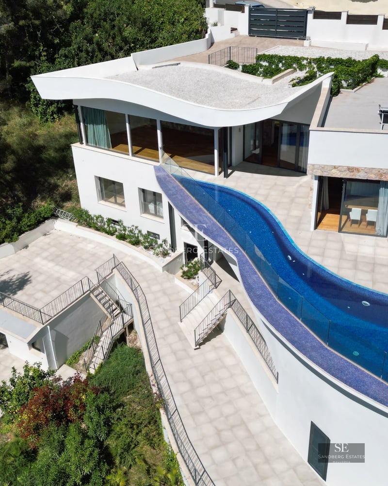 Bright living room with floor-to-ceiling windows offering sea view. Modern furniture, light wood floors and access to the terrace. Elegant minimalist design.