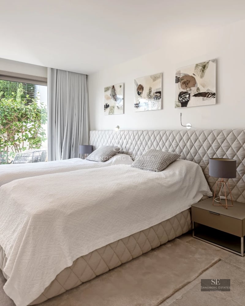 View of a luxurious villa featuring a pool, sun loungers, and lush greenery. Modern architecture with large windows.