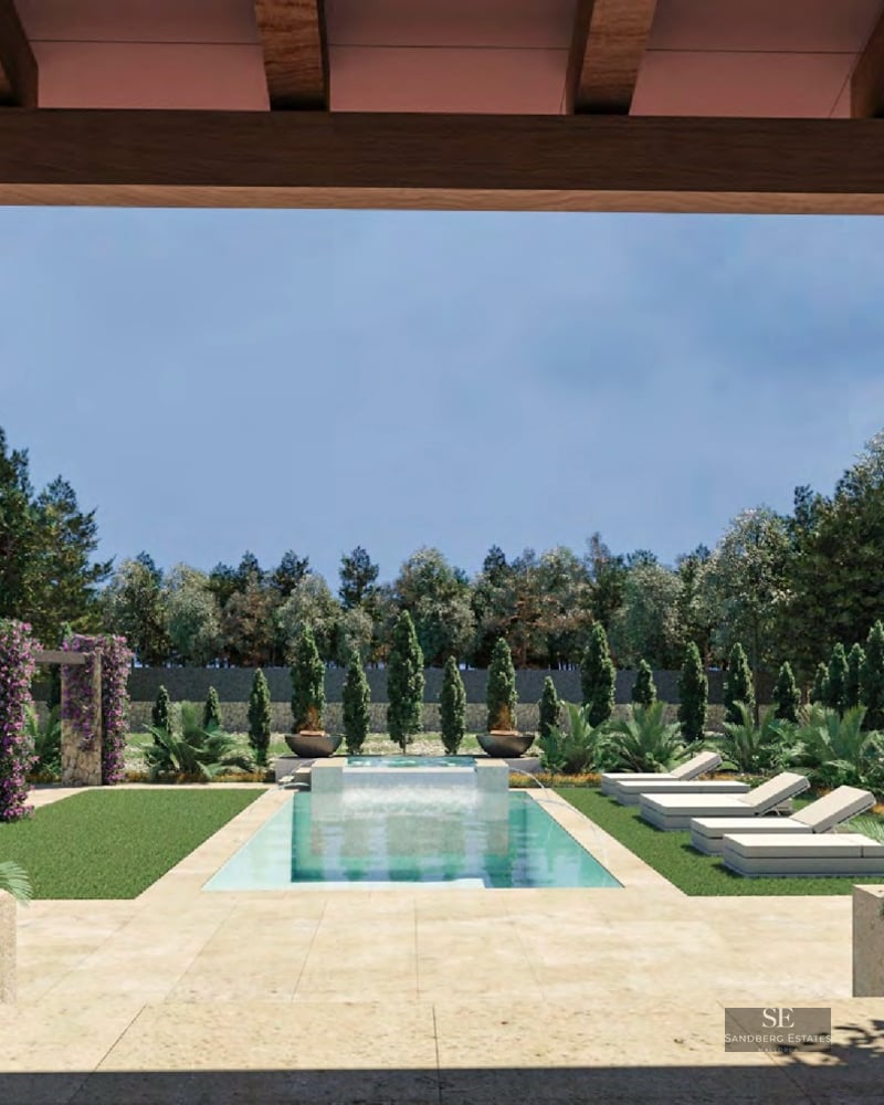 View of a turquoise swimming pool from a stone porch, surrounded by green lawn and purple flowers.