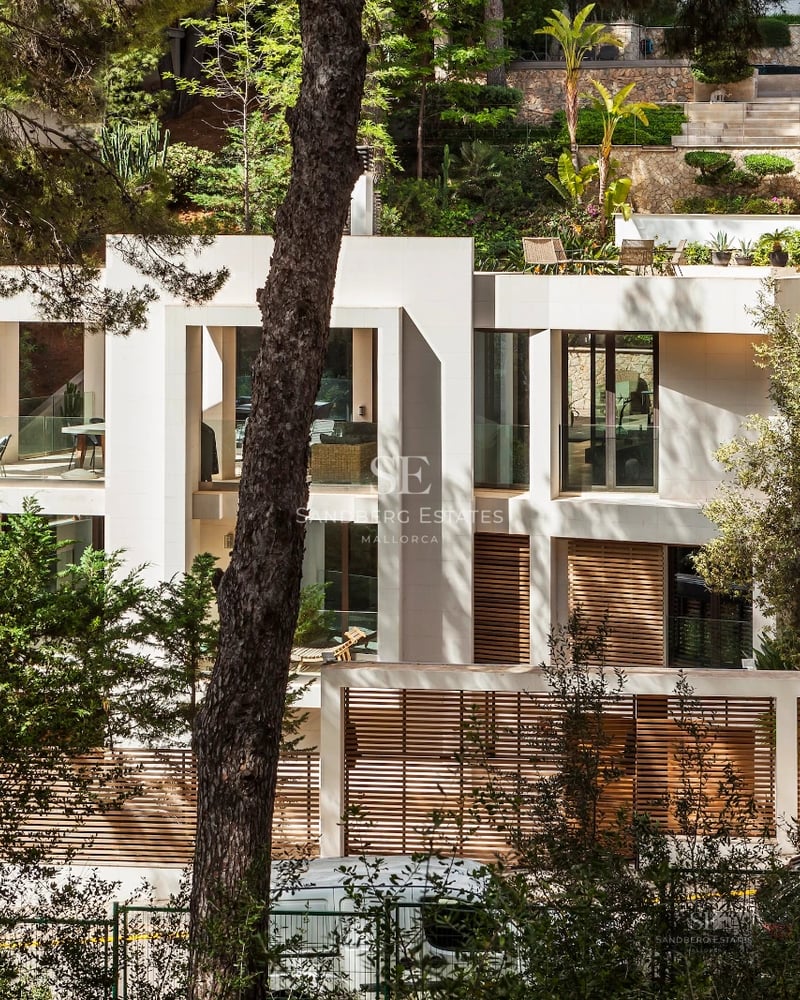 Spacious balcony with panoramic sea views. Modern and elegant furniture, light wood flooring, glass railing. Clear blue sky.