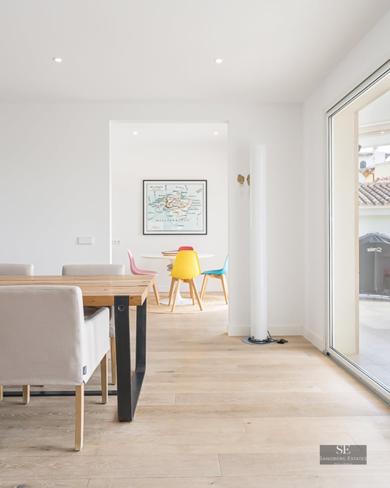 Salle à manger spacieuse avec table en bois, chaises beiges et baies vitrées ouvrant sur une terrasse.