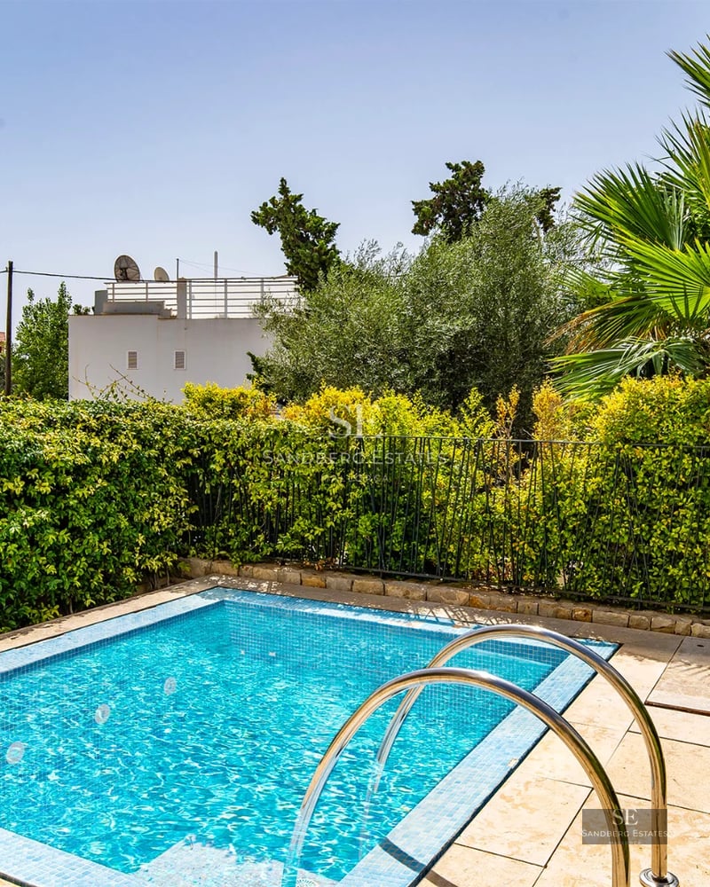 Spacious living room with floor-to-ceiling windows, wood floors, modern fireplace, and stunning views. Grey sofas, glass coffee table. Contemporary design.