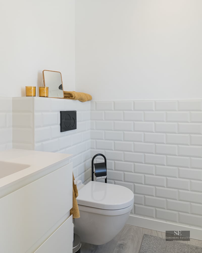 Modern white bathroom featuring subway tiles, black fixtures, and a sleek minimalist vanity.