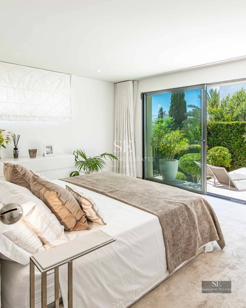 Exterior view of a modern villa featuring an infinity pool, manicured garden, and spacious terraces. Minimalist architecture with large windows.