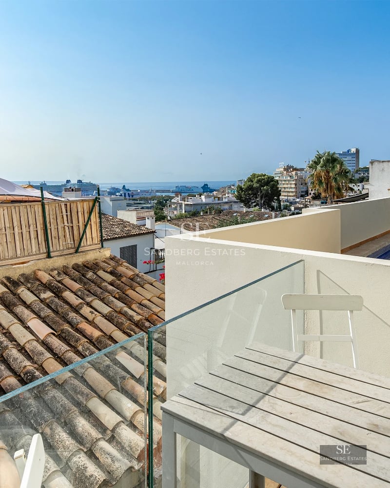 Bright living room with large windows overlooking the sea, modern and elegant design. Beige sofa, wooden coffee table, and minimalist decorative touches.