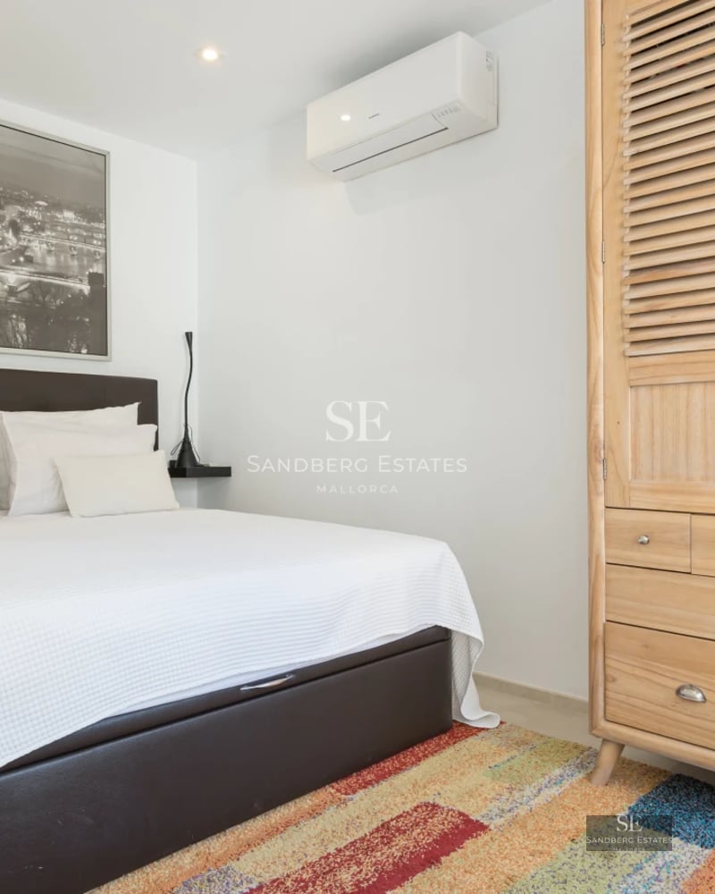 Spacious living room with panoramic windows, sea view, light wood floors and modern furnishings in neutral tones.