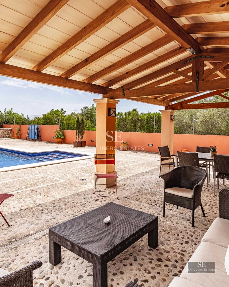 View of modern villa with infinity pool, lush garden, and sleek architectural design. Expansive glass windows and terraces.