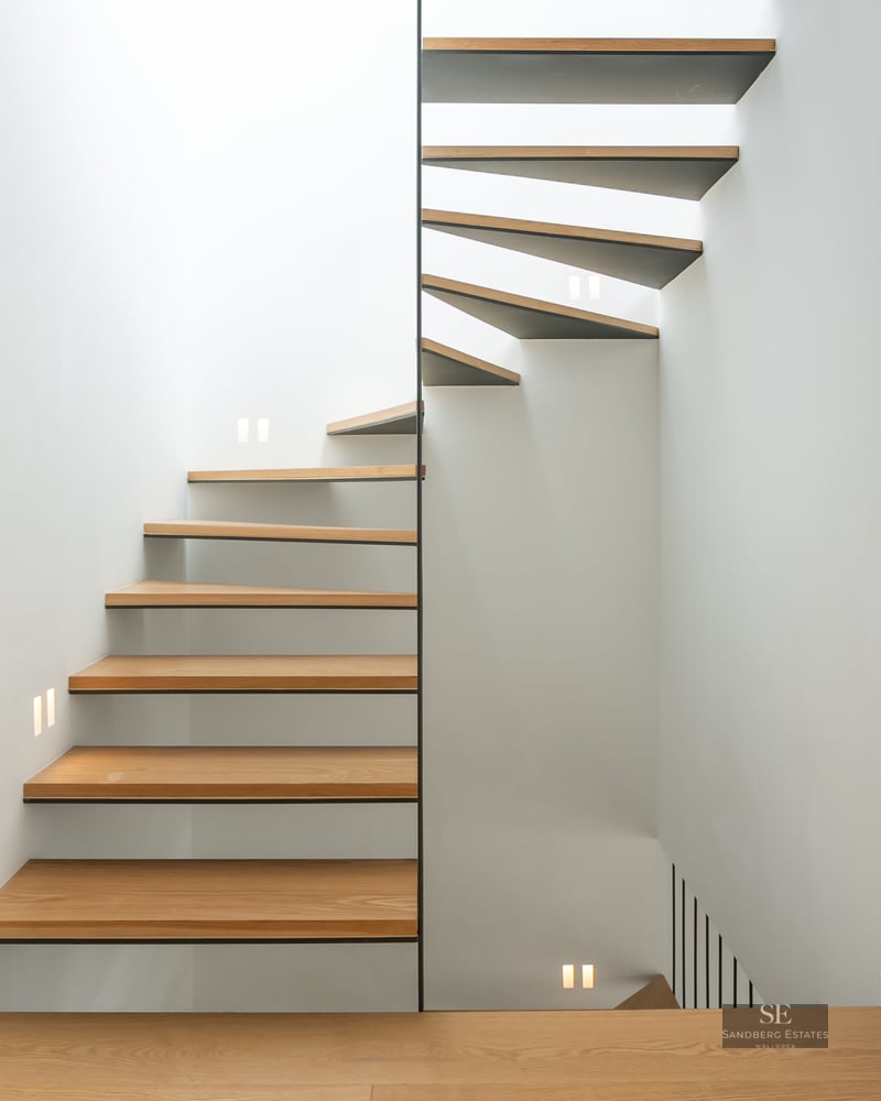 Modern spiral staircase with oak steps and white walls featuring integrated LED square lights.