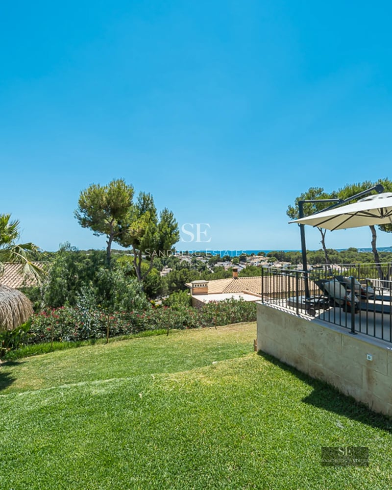Salon spacieux avec grandes baies vitrées et balcon avec vue sur la mer. Intérieur moderne avec canapés design et lumière naturelle abondante.