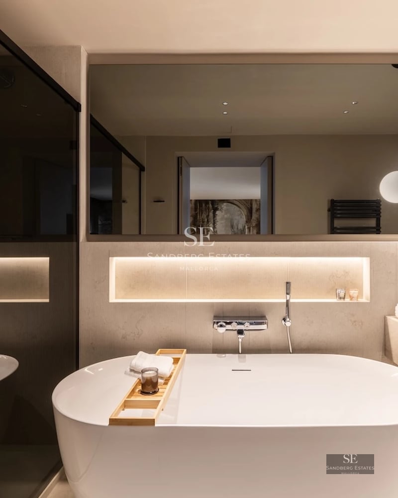 Spacious balcony with sea view. Glass railing, grey tile floor, and modern furniture. Soft ambient lighting.