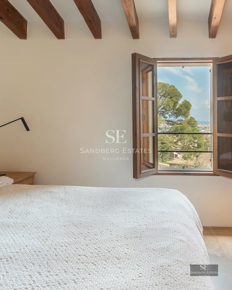 View of infinity pool surrounded by lush garden and modern villa with large windows and minimalist architecture.