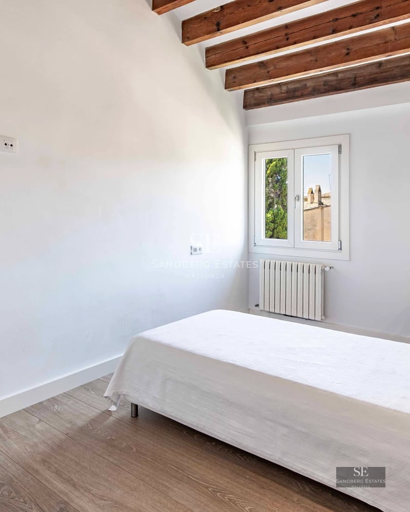 Bright living room with floor-to-ceiling windows, light wood floors, and balcony access with sea views. Modern and elegant decor.