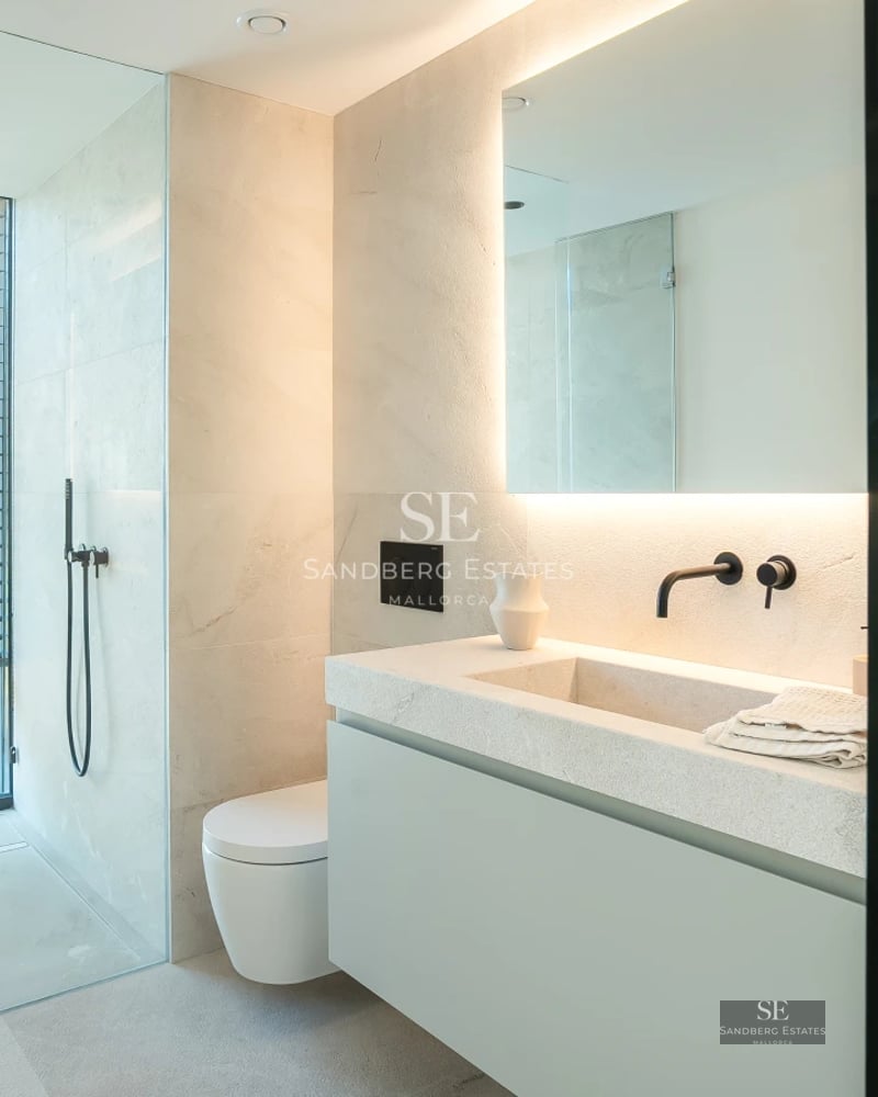 Large balcony overlooking the sea. Glass railing, wooden floor, modern outdoor furniture and infinity pool in the background.