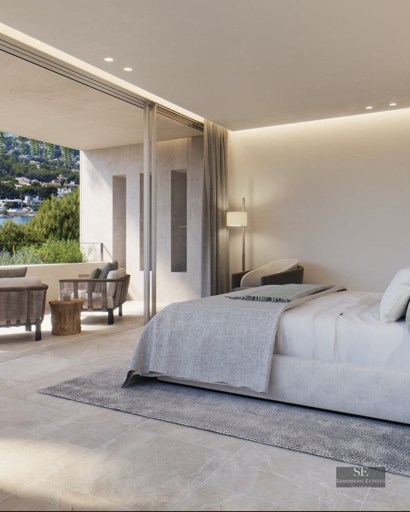 Luxury master suite featuring a large bed, stone floors, and a private terrace overlooking a scenic coastal bay.