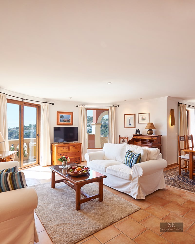 Spacious living room with white sofas, terracotta floors, a fireplace, and a dining area with wooden furniture.