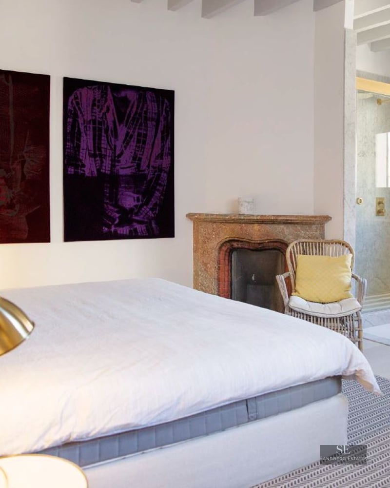 Contemporary master bedroom featuring a rustic fireplace, marble ensuite shower, and elegant brass lighting.