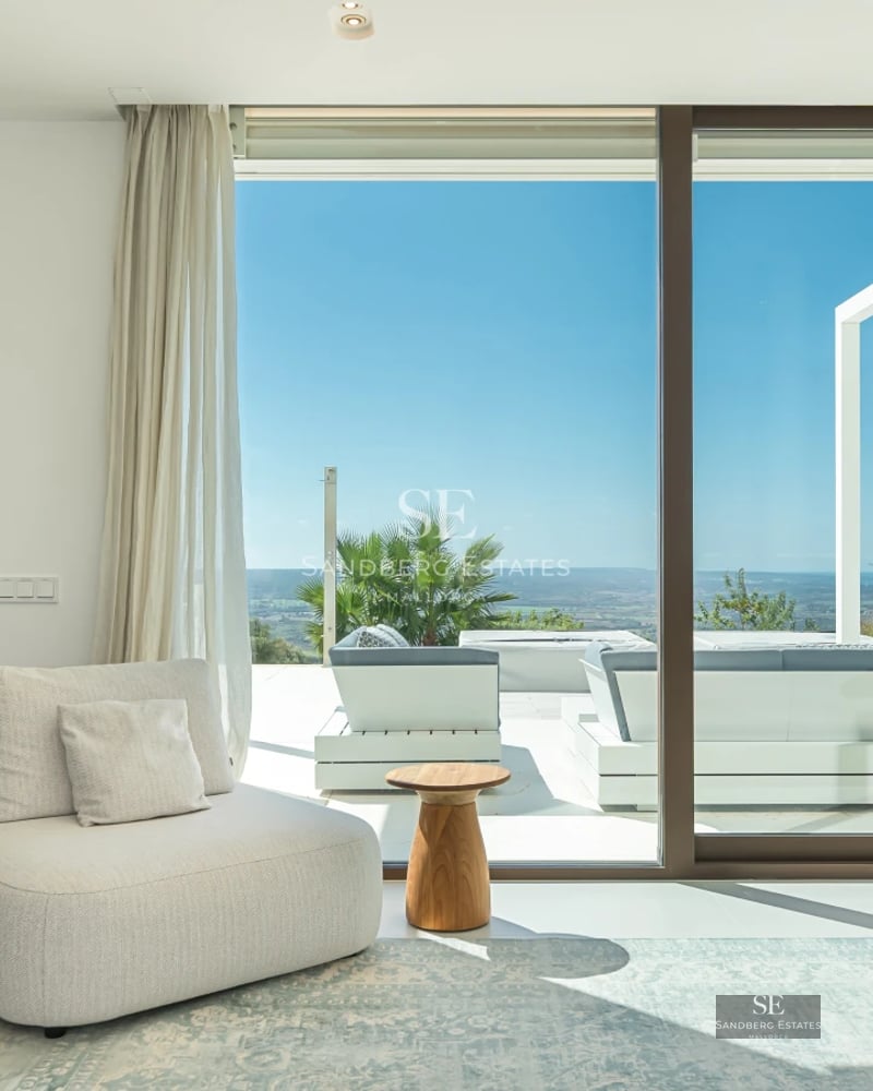 Bright living room with sea view through panoramic windows, light wood floors and modern furniture in neutral tones. Elegant design and panoramic views.